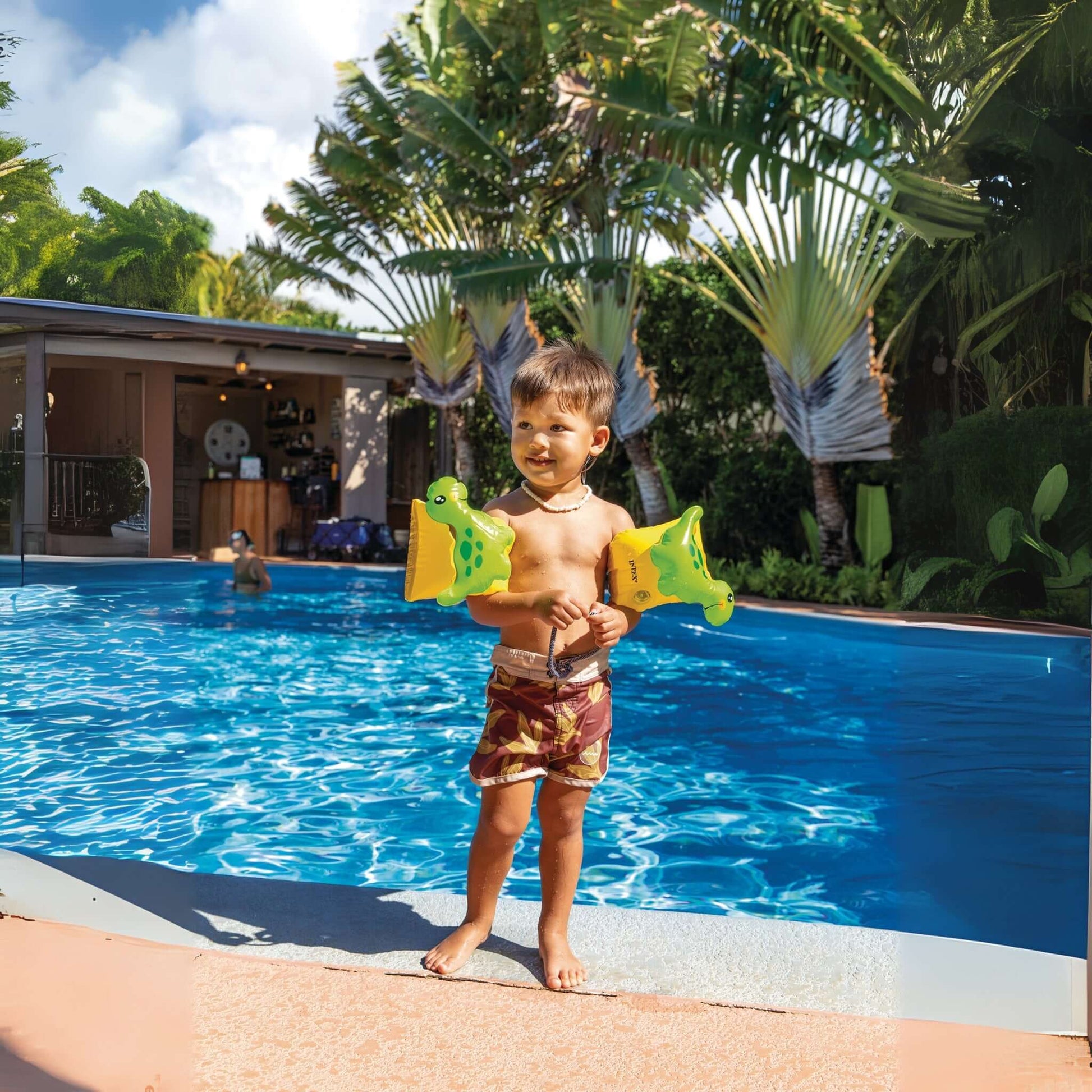 Toddler wearing Intex Dinosaur Arm Bands by Discount Pool Mart DPM, enjoying at poolside in sunny weather, SKU 32132J.