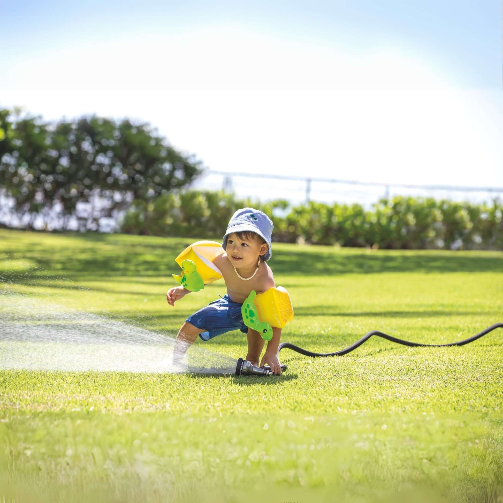 Toddler playing with Intex Dinosaur Arm Bands in the yard, enjoying water play. SKU: 32132J - Discount Pool Mart DPM