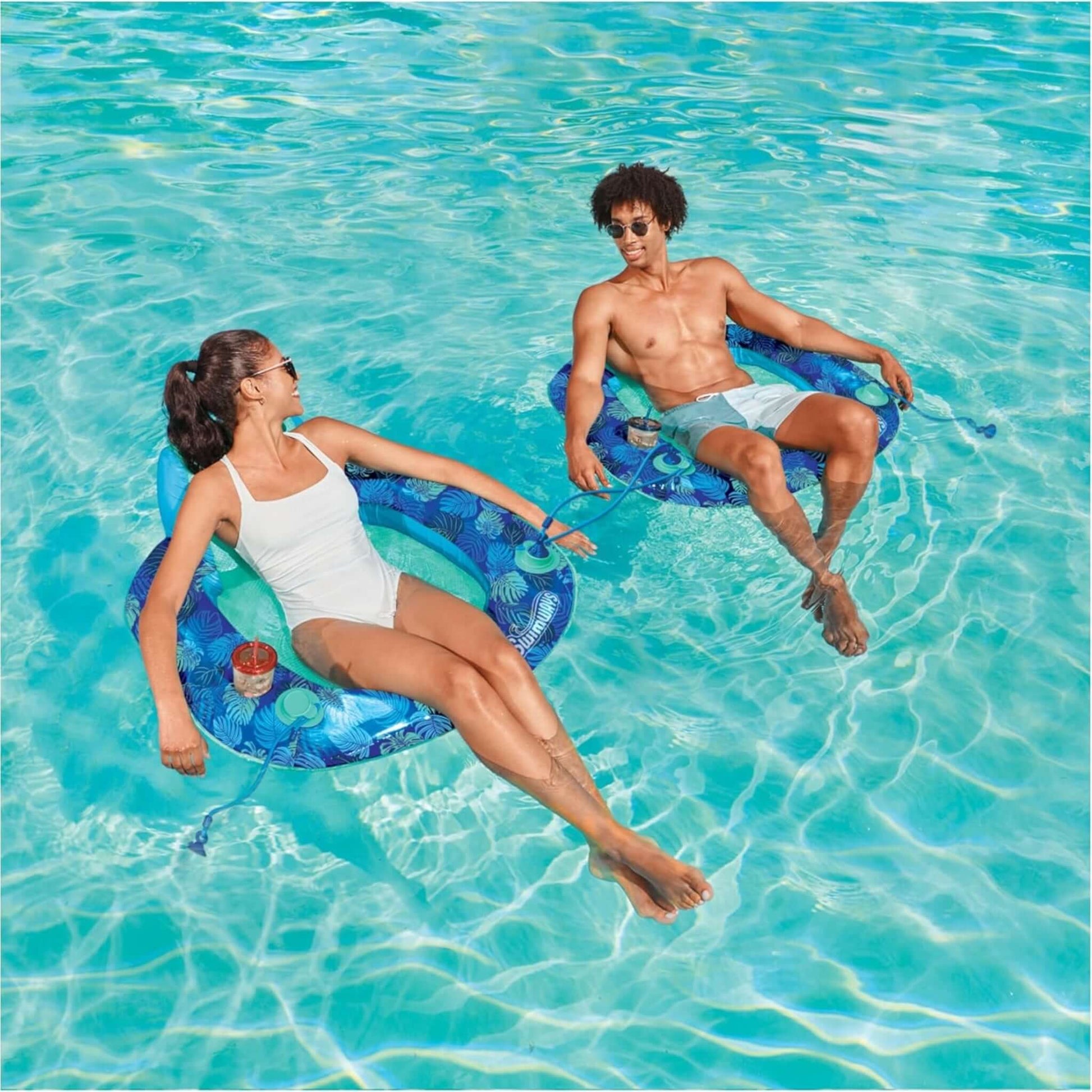 Two people relaxing on SwimWays Elite Spring Float Sunseat in a pool, SKU 6069309, by Discount Pool Mart DPM.