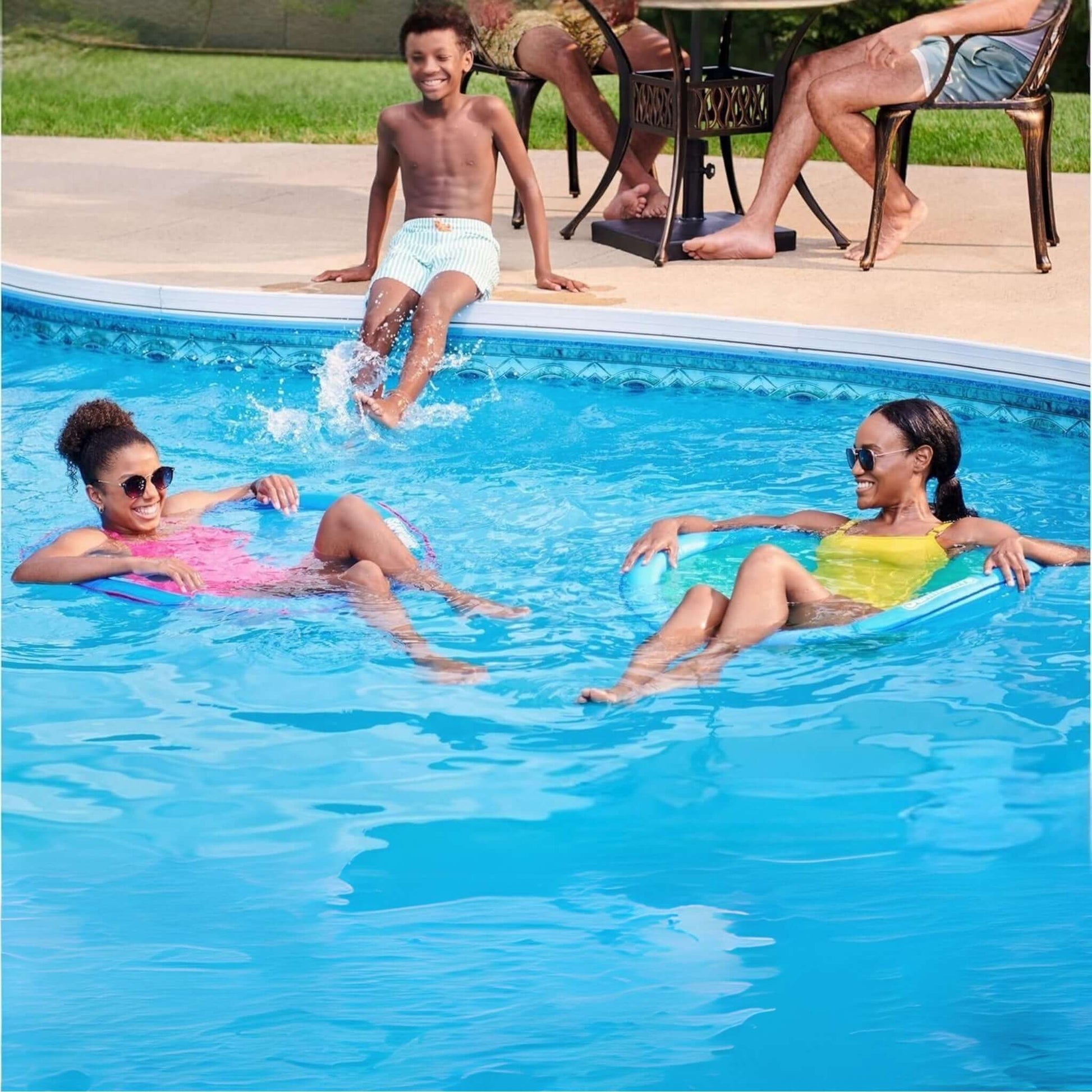 Family enjoying summer fun in pool with SwimWays Premium Spring Float Papasan for relaxation and splashes.