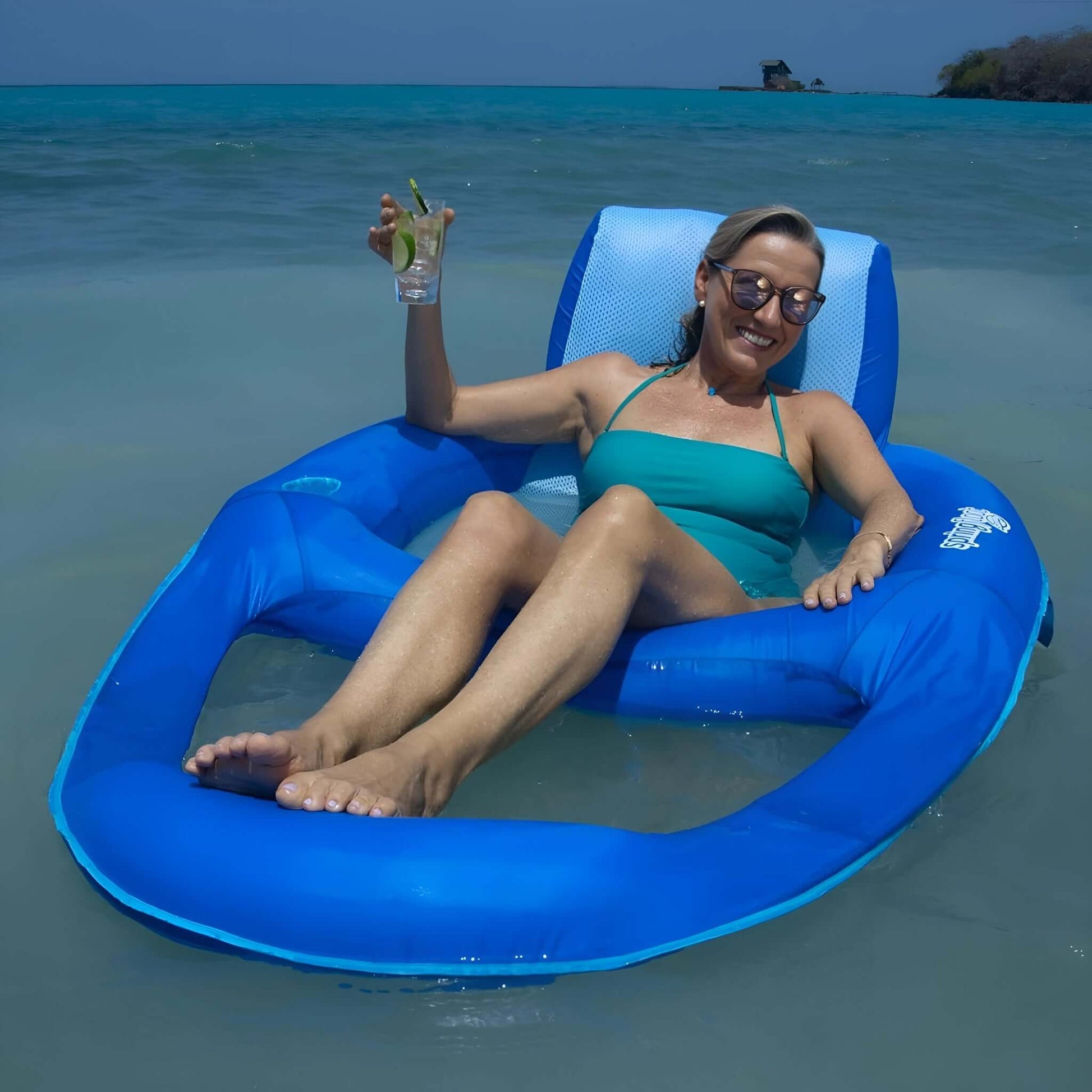 Woman relaxing in SwimWays Spring Float Recliner XL in water, enjoying a drink. SKU: 6069706, Discount Pool Mart DPM.