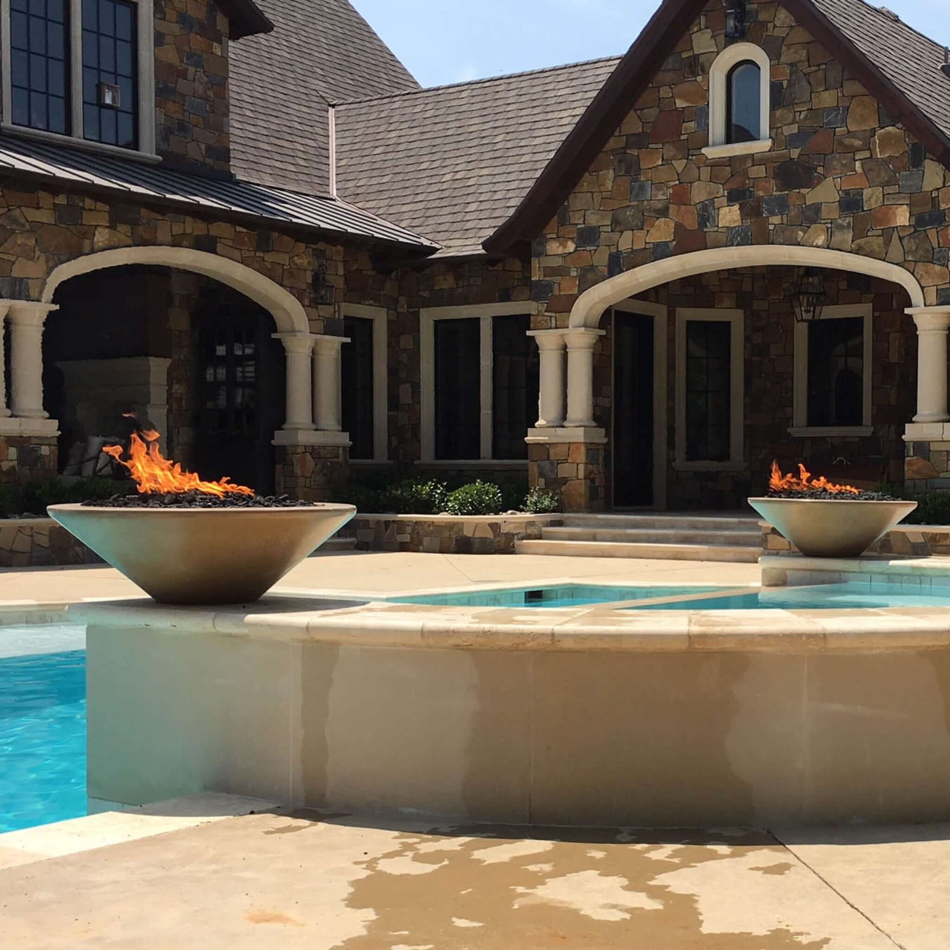 Outdoor Plus Cazo Fire Bowl GFRC Concrete by Discount Pool Mart DPM with flames in outdoor setting.