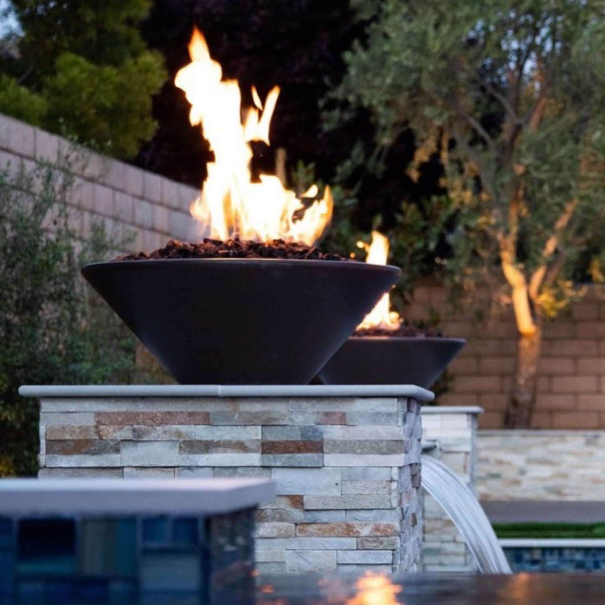 The Outdoor Plus Cazo Fire Bowl GFRC Concrete feature with flames, perfect for outdoor settings. SKU: DPM. Discount Pool Mart.