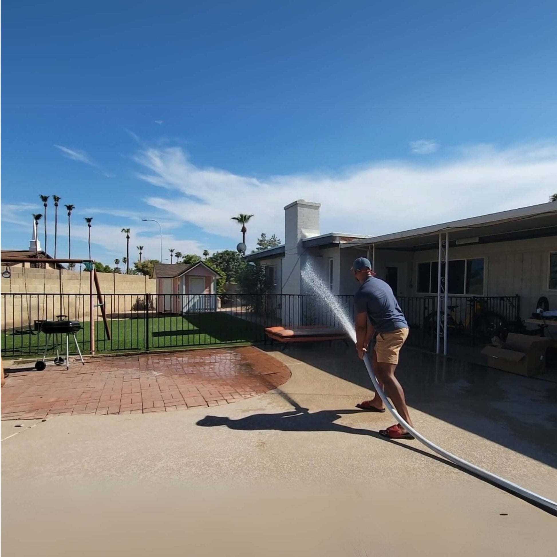 Man using FireFighter1 Fire Hose from Discount Pool Mart DPM to spray water in backyard for fire safety.