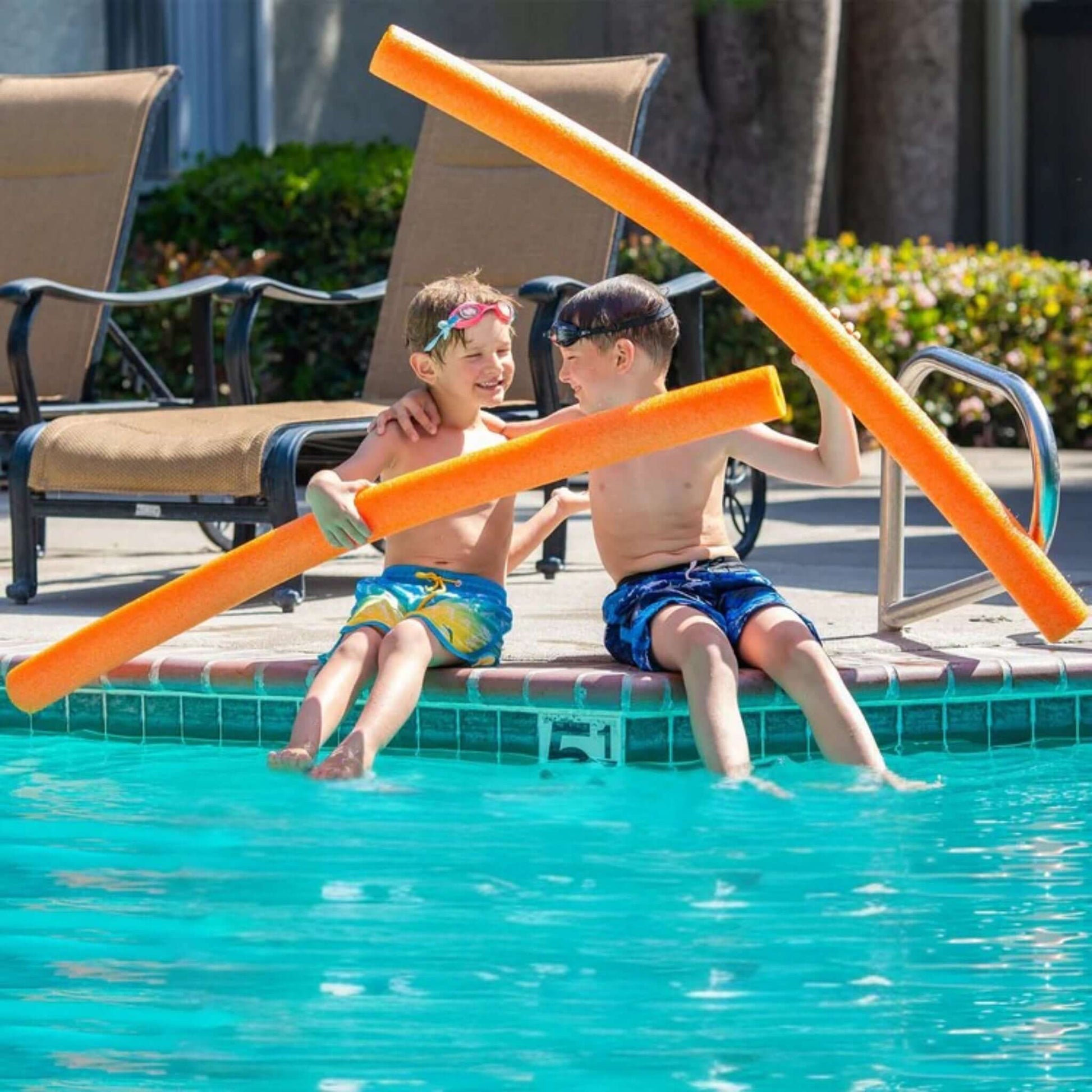 Two children enjoying summer fun with Deluxe Foam Swim Noodles in a vibrant orange color by Discount Pool Mart DPM. SKU: 47" x 2.25".
