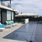 Wide-angle view of EnergyGuard™ solar pool cover fully covering an inground pool, taken from an elevated deck.