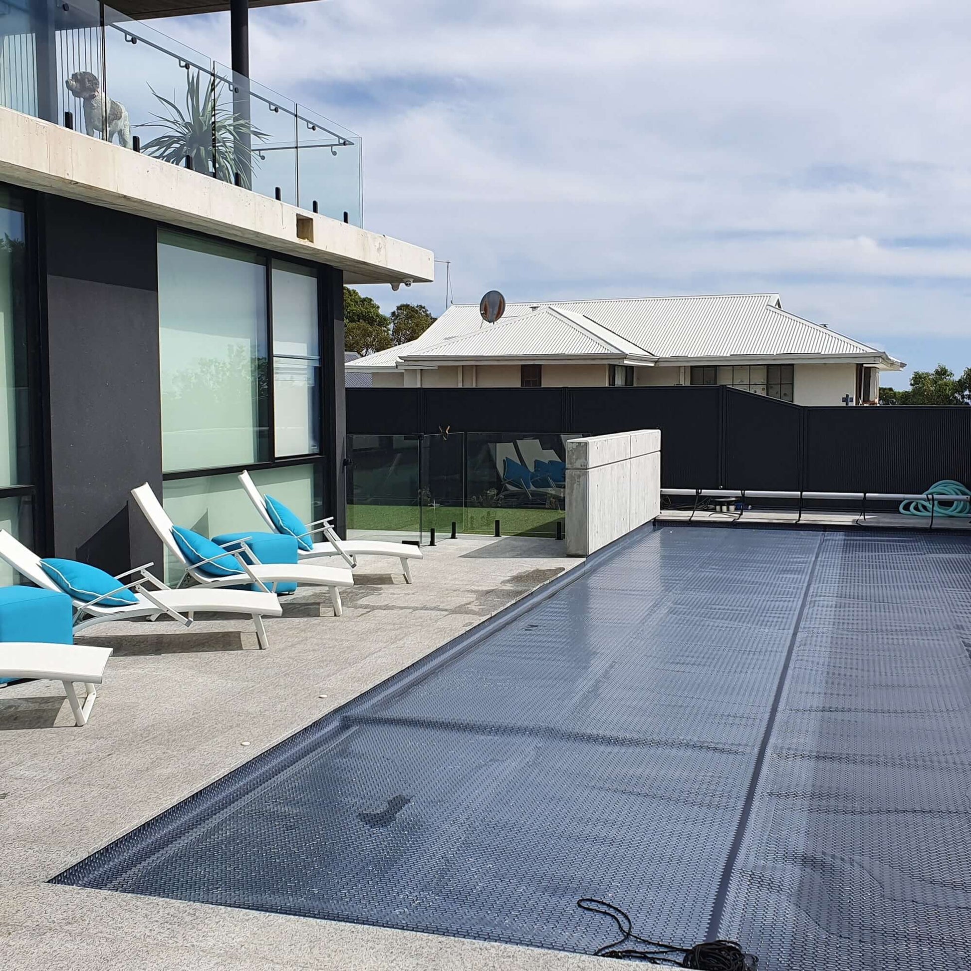 Wide-angle view of EnergyGuard™ solar pool cover fully covering an inground pool, taken from an elevated deck.