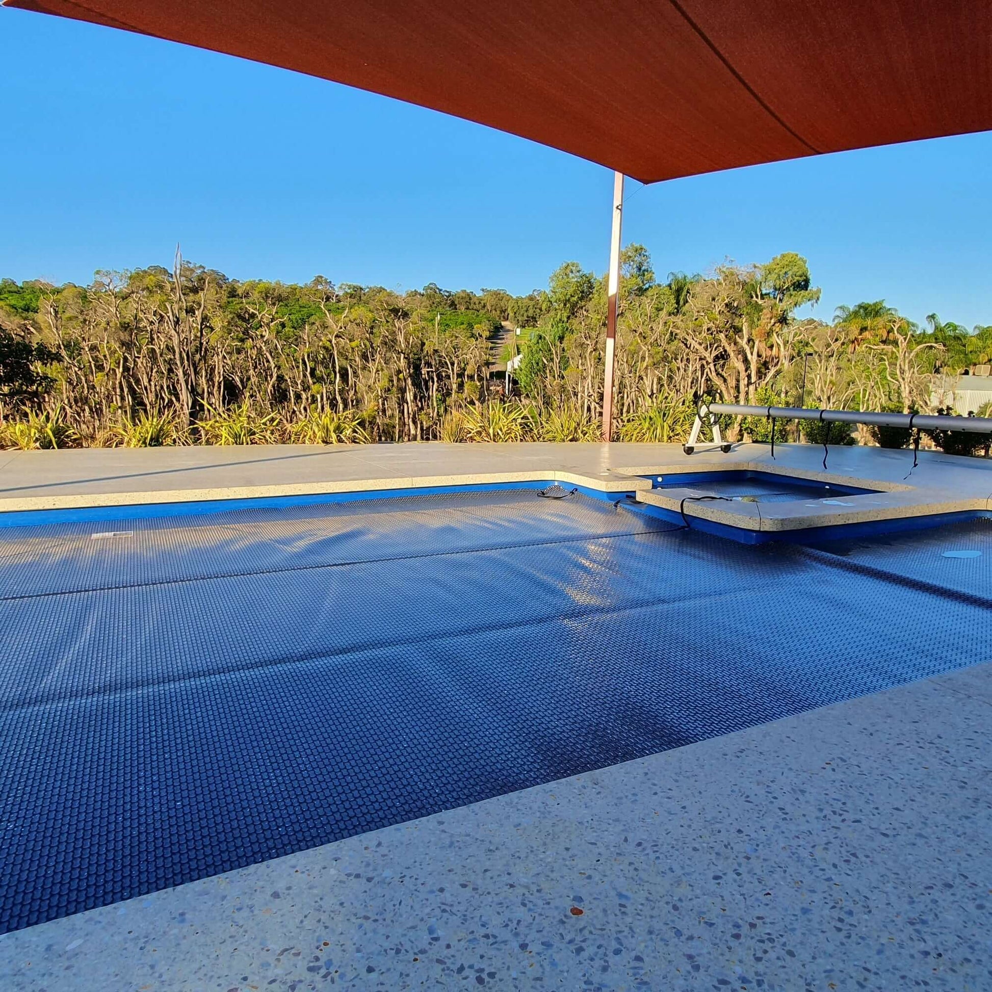 GeoBubble™ EnergyGuard™ pool cover installed on a rectangular backyard pool, fully unrolled.